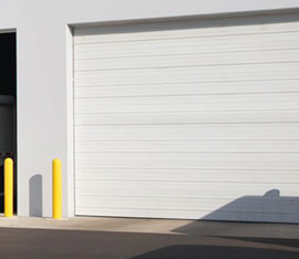 A white garage door with yellow post and shadow.