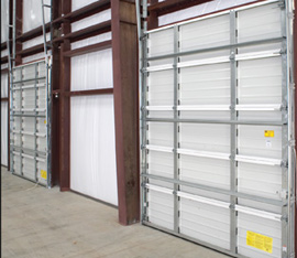 A warehouse with two white garage doors and some yellow stickers on the side of it.